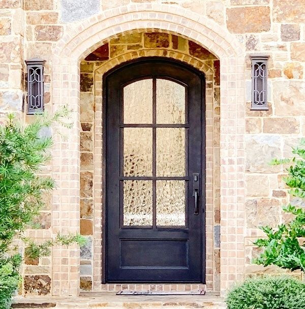 Brick home with black iron front door with Flemish glass